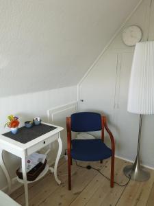 Habitación con mesa, silla azul y escritorio. en Rosenhuset, en Haderslev