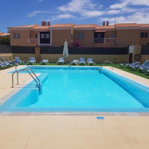 a large swimming pool with chairs and a house at VILLA 16 LUJO A 200 M DEL MAR in Corralejo