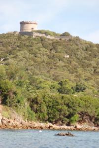 a castle on top of a hill next to the water at HOTEL CAMPOMORO in Belvédère-Campomoro