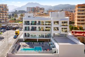 a white building with a pool in front of a city at Carihuela Suites in Torremolinos