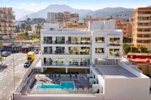 un edificio blanco con piscina frente a una ciudad en Carihuela Suites, en Torremolinos