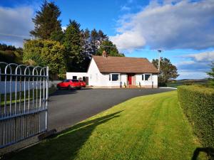 a white house with a red car parked in a driveway at Alice's Cottage in Omagh