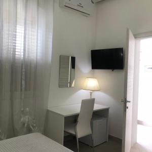 1 dormitorio con escritorio y TV en la pared en casa ginevra en Porto Cesareo