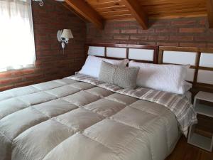 a large white bed in a room with a brick wall at Casamia Altos in Bahía Blanca