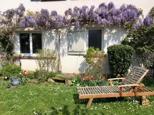 un banc en bois dans un jardin avec des fleurs violettes dans l'établissement Le Rez de Jardin, à Illkirch-Graffenstaden