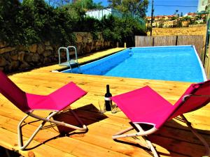 2 sillas rosas sentadas en una terraza junto a una piscina en Moab Palaces en Arad
