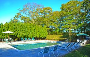 einen Pool mit Stühlen und Sonnenschirmen neben in der Unterkunft Southampton Long Island Hotel in Southampton