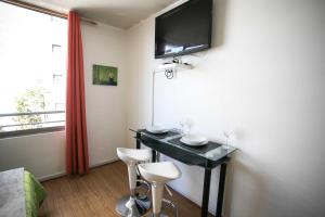Habitación con mesa con 2 sillas y TV. en Apartments Zenteno, en Santiago
