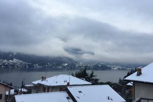 a view of a lake with snow on the roofs of houses at La casa degli ulivi in Lierna