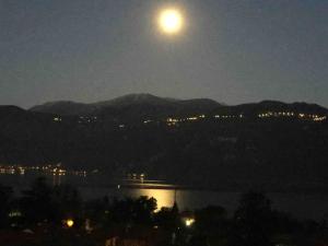 a full moon rising over the water at night at La casa degli ulivi in Lierna