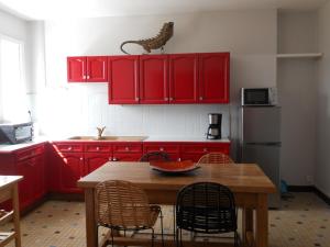 una cocina con armarios rojos y una mesa de madera con sillas. en LE PETIT SARMENTIN, en Saint-Romain-sur-Cher