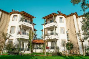 une rangée d'immeubles d'appartements avec des arbres devant dans l'établissement Aloria Garden Hotel, à Erdek