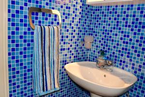 a blue tiled bathroom with a sink and a towel at Studio apartments Morinj in Donji Morinj