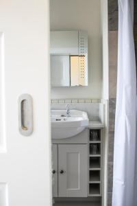 La salle de bains est pourvue d'un lavabo et d'une armoire blanche. dans l'établissement Linndhu House, à Tobermory