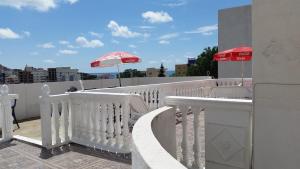 a white railing with an umbrella on a balcony at Guesthouse Ada in Bar