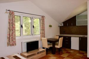 a kitchen with a table and a tv in a room at Studio apartments Morinj in Donji Morinj