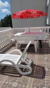 a cocacola umbrella sitting next to a table and a chair at Guesthouse Ada in Bar