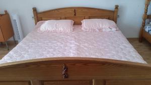 a large wooden bed with two pillows on it at Guesthouse Ada in Bar