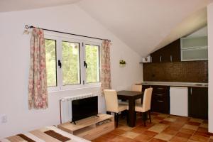 a kitchen with a table and a tv in a room at Studio apartments Morinj in Donji Morinj +25 photos