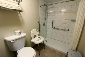 a white toilet sitting next to a bath tub in a bathroom at Super 8 by Wyndham Kelowna BC in Kelowna