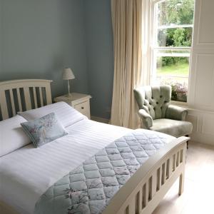 a bedroom with a bed and a chair and a window at Riversdale Country House in Malin