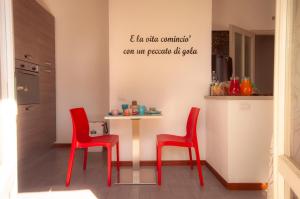 una cocina con sillas rojas y una mesa con un cartel en la pared en B&B Cento Passi Dalle Mura, en Lucca