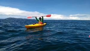 a man in a yellow kayak in the ocean at Luquina homestay in Puno