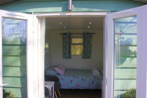 a small bedroom with a bed in a window at Hopgarden Glamping Luxury Shepherds Huts in Wadhurst