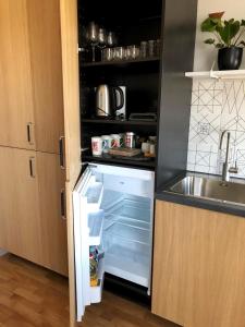 an empty refrigerator with its door open next to a sink at Kaktuss apartamenti Smiltene in Smiltene