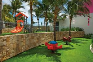 a park with a playground with a slide and palm trees at Krystal Grand Cancun in Cancún