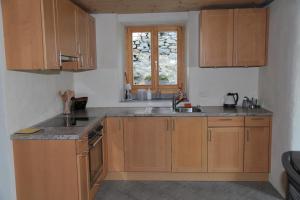 eine Küche mit Holzschränken, einem Waschbecken und einem Fenster in der Unterkunft Casa Flora in Verdabbio