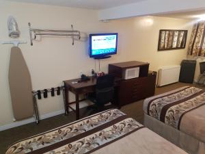 a hotel room with two beds and a desk with a television at Parkway Motel & European Lodges in Pincher Creek