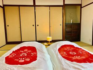 two beds with red and white covers in a room at Private reservation near KIX "Wakeikan" in Hannan
