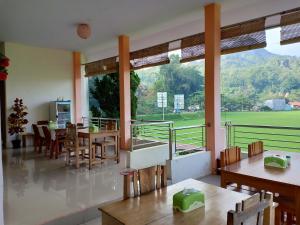 een eetkamer met tafels en stoelen en een groot raam bij Rosalina Homestay in Rantepao