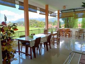 uma sala de jantar com mesas e cadeiras e uma varanda em Rosalina Homestay em Rantepao