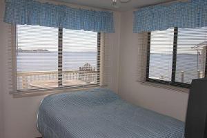 a bedroom with a bed and two large windows at Montego Bay - South Ocean Drive 203 in Ocean City +1 photo