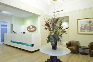 a lobby with a table with a vase of flowers on it at Seasons Heritage Melbourne in Melbourne