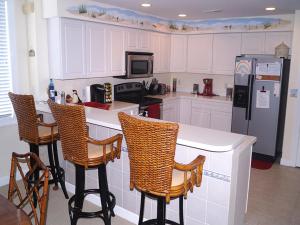 a kitchen with white cabinets and a counter with chairs at Ocean'S Edge 401 Condo in Ocean City