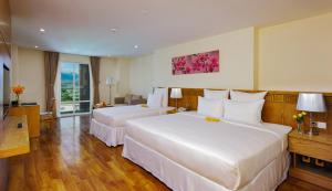 a hotel room with two beds and a window at Rosaka Nha Trang Hotel in Nha Trang