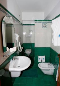 baño verde y blanco con lavabo y aseo en Hotel Tesoriero en Panarea