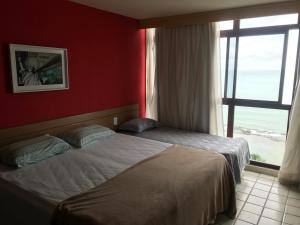 a hotel room with two beds and a window at Heliodoro Flat Golden Beach in Recife