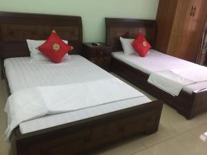 2 Betten mit roten Kissen in einem Zimmer in der Unterkunft Hân hân in Hạ Long