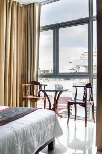 een slaapkamer met 2 stoelen, een bed en een raam bij Hotel Thu Ha - Sân bay Tân Sơn Nhất in Ho Chi Minh-stad