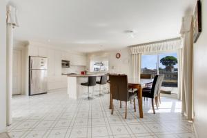 a kitchen with a table and chairs and a refrigerator at Tondo in Lakes Entrance