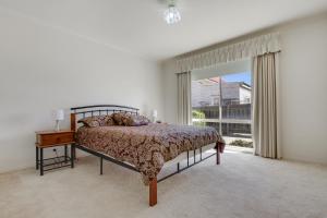 a bedroom with a bed and a large window at Tondo in Lakes Entrance