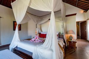 a bedroom with a canopy bed with white drapes at Villa Taman di Blayu by Nagisa Bali in Tabanan