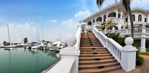 une maison blanche avec des escaliers et des bateaux dans l'eau dans l'établissement Avillion Admiral Cove, à Port Dickson