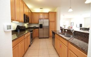 a kitchen with wooden cabinets and a stainless steel refrigerator at Shoreway Condo #231524 in Orlando