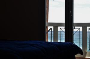 1 dormitorio con cama azul y ventana grande en Aegean View, en Platána