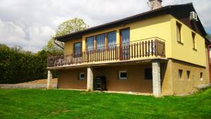 uma casa amarela com uma varanda no topo de um quintal em Chalupa Ratibořice em Česká Skalice